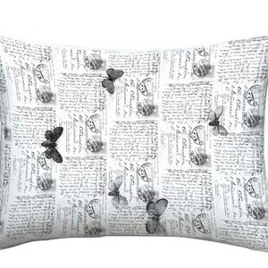 May include: Rectangular decorative pillow with a vintage postcard design. The white pillow features a repeating pattern of old postage stamps, handwritten script, and grayscale butterfly illustrations. A charming accent for any room.