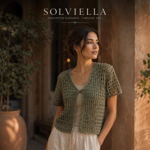 Könnte beinhalten: Eine olivgrüne kurzärmelige Häkelstrickjacke mit V-Ausschnitt und einem einzelnen Bindeband vorne. Der Text SOLVIELLA CROCHETED ELEGANCE, TIMELESS YOU. ist oben sichtbar. Das Kleidungsstück hat ein offenes Strickmuster und kurze Ärmel.