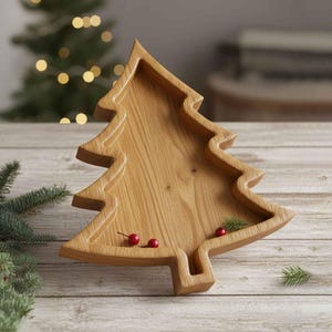 May include: Wooden Christmas tree-shaped serving tray. The tray is made of light-colored wood and has a carved design. Red berries and green sprigs are placed inside the tray. The tray is on a wooden surface.