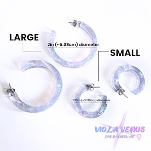 May include: Two pairs of translucent hoop earrings with iridescent flakes. The large pair has a 2-inch diameter, and the small pair has a 1.25-inch diameter. The image includes the text LARGE, SMALL, and VIOLA VENUS JEWELRY & RESIN ART.