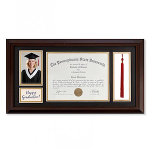 May include: A framed graduation display featuring a photo of a graduate in a cap and gown, a diploma from Pennsylvania State University, and a red tassel. The frame includes the text "Happy Graduation!"