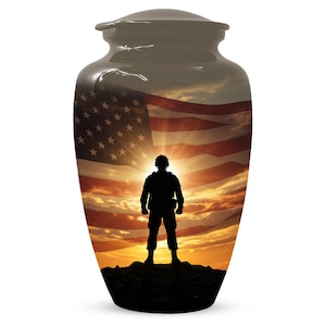 May include: A dark-coloured urn with a glossy finish. The urn features an image of an American flag and a silhouette of a soldier standing on a hill against a sunset backdrop. The urn has a lid.