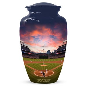 Puede incluir: Una urna azul marino con una escena de estadio de béisbol. La urna presenta un cielo al atardecer y un campo de béisbol con jugadores. El número "1129" está impreso en la parte inferior. Un artículo decorativo para fines conmemorativos.