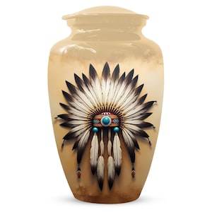 May include: Cream-coloured urn with a Native American headdress design. The headdress features black and white feathers, turquoise accents, and a red band. The urn has a lid and a glossy finish.