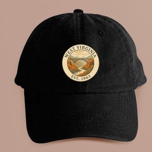 May include: Black baseball cap with a circular patch featuring a bridge over a river, surrounded by autumn foliage. The patch reads "WEST VIRGINIA EST. 1863". The cap is made of a durable fabric and has a curved brim.