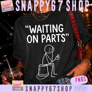 Könnte beinhalten: Ein schwarzes T-Shirt mit dem weißen Text "WAITING ON PARTS" über einer Grafik eines Strichmännchens, das auf einem Eimer sitzt und eine kleine Schraube hält. Das Design ist in einer klaren Schrift gedruckt und das Shirt hat eine lockere Passform.