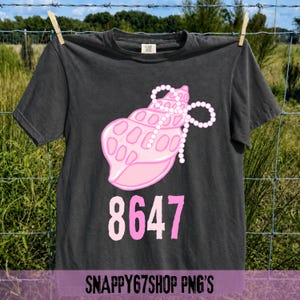 Könnte beinhalten: Dunkelgraues T-Shirt mit einem rosa Muschelgrafik-Design, einer weißen Perlenkette und der rosa Zahl 8647. Das T-Shirt hängt an einer Wäscheleine. Der Text "SNAPPY67SHOP PNG'S" befindet sich unten.