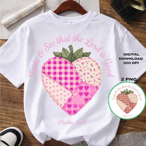 Könnte beinhalten: Weißes T-Shirt mit einem herzförmigen Erdbeerdesign, das verschiedene rosa Muster und grüne Blätter aufweist. Der Text "Taste & See that the Lord is Good" und "Psalm 34:8" sind ebenfalls vorhanden. Eine kleinere Grafik ist ebenfalls sichtbar.