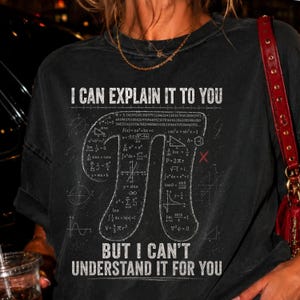 Könnte beinhalten: Ein anthrazitfarbenes Kurzarm-T-Shirt mit dem weißen Text I CAN EXPLAIN IT TO YOU oben und BUT I CAN'T UNDERSTAND IT FOR YOU unten. In der Mitte befindet sich ein großes Pi-Symbol, das mit verschiedenen weißen mathematischen Formeln gefüllt ist.