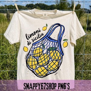 May include: Cream-colored t-shirt with a graphic of lemons in a blue net bag. The text "limoni di sicilia" is above the bag. The shirt is hanging on a clothesline. The bottom of the image has the text "SNAPPY67SHOP PNG'S".