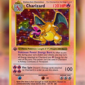 May include: A holographic Charizard trading card featuring a yellow border, a fire-type symbol, and 120 HP. The card displays the Stage 2 evolution, the Energy Burn Pokémon Power, and the Fire Spin attack with a 100 damage value and 1st edition stamp.