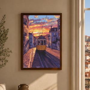以下が含まれることがあります： 夕暮れ時の街の通りで、石畳の線路を走る黄色い路面電車を描いた額入りアートプリント。両側に並ぶ高い建物、頭上の架線、そして地平線の上に広がる鮮やかなオレンジと紫の空が特徴的な風景画です。