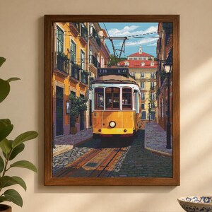 May include: A framed print depicting a yellow tram on a cobbled street in Lisbon, Portugal. The buildings are painted in shades of yellow and orange. The tram's clock shows 2:11 and 12:47. The print is displayed on a wooden surface with books.
