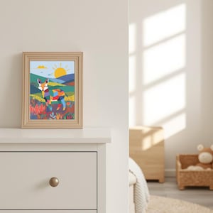 Puede incluir: Una impresión artística enmarcada que presenta una colorida ilustración de un zorro en un paisaje con un sol y montañas. El zorro está representado con formas geométricas en varios colores. El marco es de madera clara.