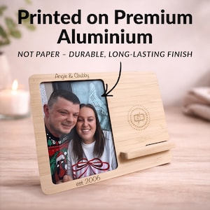 May include: A wooden photo frame with a picture of a couple, featuring the text "Angie & Chubby" and "est. 2006". The frame has a built-in wireless charger and the text "Printed on Premium Aluminium" and "NOT PAPER - DURABLE, LONG-LASTING FINISH".