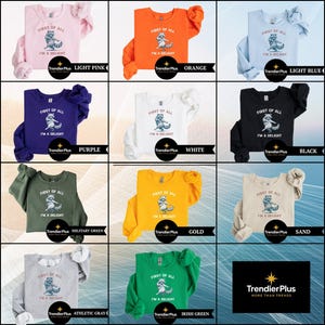 May include: A collection of sweatshirts in various colors, each featuring a raccoon graphic and the text "FIRST OF ALL I'M A DELIGHT." Colors include light pink, orange, light blue, purple, white, black, military green, gold, sand, athletic gray, and Irish green.
