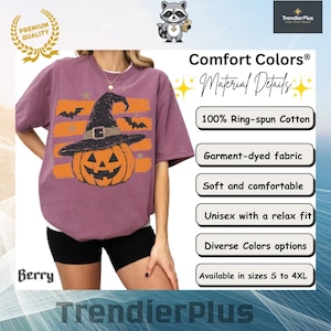 Puede incluir: Una camiseta color baya con un gr&aacute;fico de una calabaza naranja con un sombrero de bruja negro, sobre rayas horizontales naranjas y murci&eacute;lagos negros. La camiseta incluye etiquetas de texto para Comfort Colors y 100% algod&oacute;n.