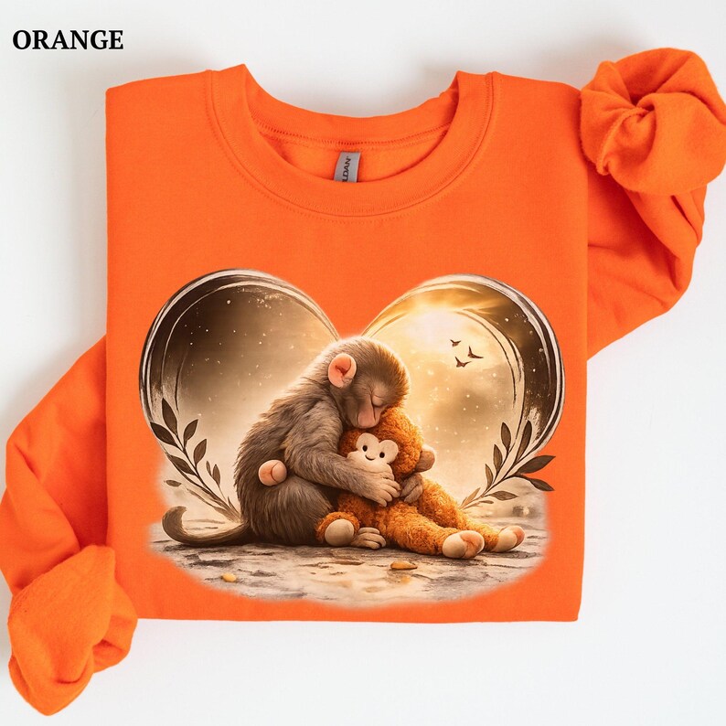Orange sweatshirt featuring a heart-shaped graphic with two hugging monkeys. One monkey is gray and the other is brown.