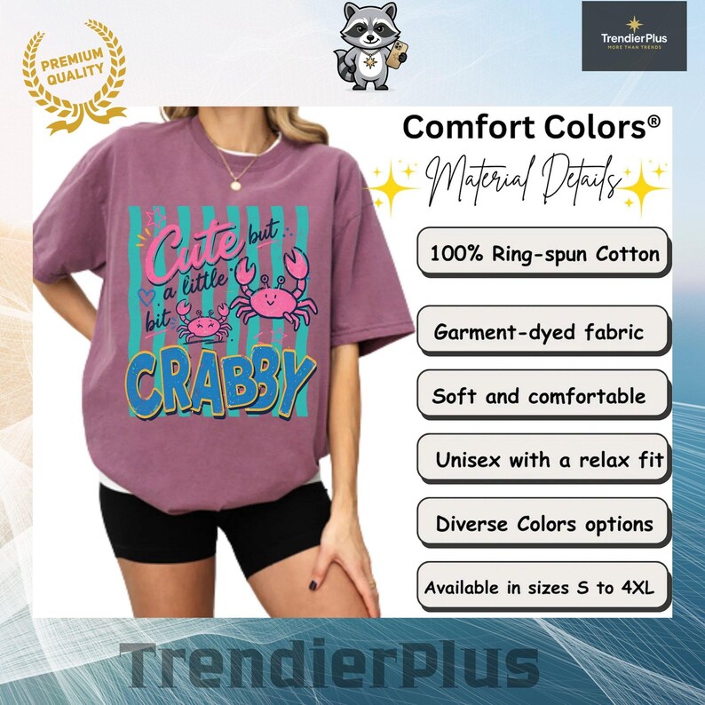 May include: A mauve short-sleeve t-shirt featuring a graphic print with two pink crabs and the text "Cute but a little bit CRABBY" in pink and blue. The design includes vertical teal stripes. The shirt is made of 100% ring-spun cotton fabric.