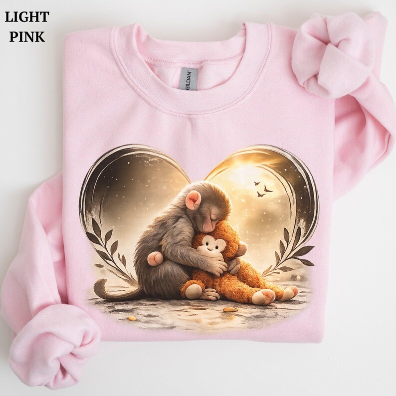 Light pink sweatshirt featuring a heart-shaped graphic with two monkeys hugging.