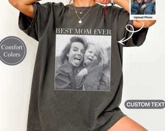May include: Pepper-colored t-shirt with the text "BEST MOM EVER" above a black and white photo of a mother and child sticking out their tongues. The shirt has a relaxed fit and is part of the Comfort Colors collection.