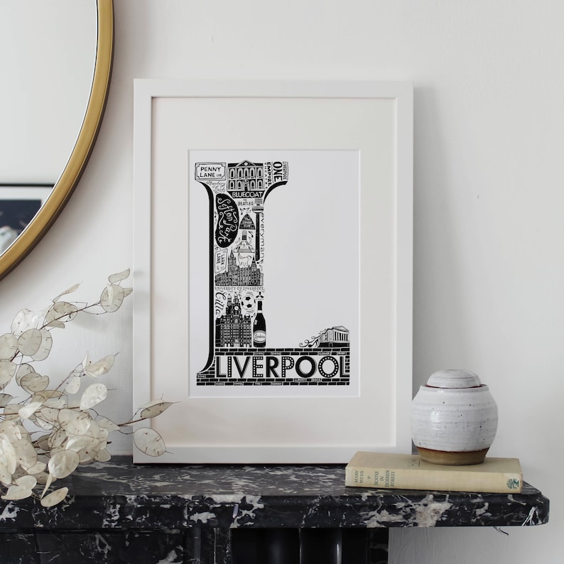 May include: Black and white illustration of the letter L made up of iconic landmarks and buildings from Liverpool, England. The word "Liverpool" is printed below the letter.