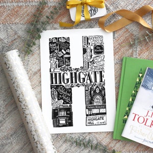 May include: A black and white print of the letter "H" filled with illustrations and the word "HIGHGATE". The print is surrounded by gift wrap, a gift tag, and books. The print features the text "WATERLOW PARK", "KENWOOD HOUSE", and "HIGHGATE HILL N19".