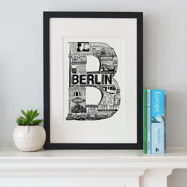 May include: Black and white illustration of the letter "B" made up of iconic landmarks and symbols of Berlin, Germany. The word "BERLIN" is written in a bold font across the center of the letter.