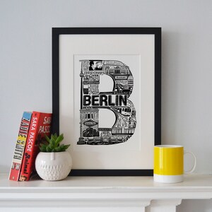 May include: Black and white illustration of the letter "B" made up of iconic landmarks and places in Berlin, Germany. The word "BERLIN" is written in bold letters across the center of the letter.