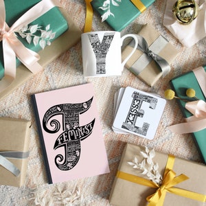 May include: A collection of gifts including a white mug with a black and white Yorkshire design, a pink notebook with the word "FEMINIST" in black, and coasters with an "ESSEX" design. The gifts are surrounded by wrapped presents.