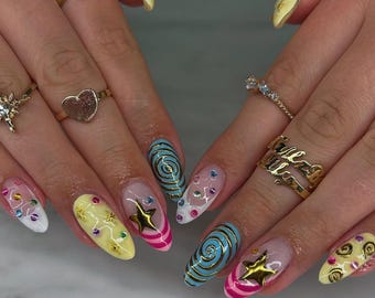 Uñas postizas con diseño de remolino Y2K, manicura retro con estrellas del pop art y temática de caramelos.