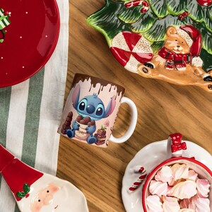 May include: A festive holiday scene with a red plate featuring gingerbread men and a gift, a Stitch mug, and a Santa-shaped plate. A Christmas tree-shaped plate and a bowl of marshmallows complete the arrangement. The items are on a wooden surface.