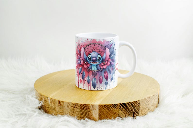 K&ouml;nnte beinhalten: Wei&szlig;e Keramiktasse mit einem farbenfrohen Aquarelldesign eines Zeichentrickcharakters und einem Traumf&auml;nger. Das Design umfasst rosa, blaue und violette Akzente. Die Tasse steht auf einem runden Holzst&auml;nder.