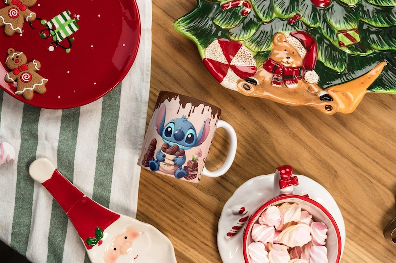 May include: A festive holiday scene with a red plate featuring gingerbread men and a gift, a Stitch mug, and a Santa-shaped plate. A Christmas tree-shaped plate and a bowl of marshmallows complete the arrangement. The items are on a wooden surface.