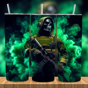 Puede incluir: Un vaso de acero inoxidable con una ilustración digital de un soldado con cara de calavera en uniforme militar, sosteniendo un rifle. El diseño incluye humo verde sobre un fondo negro. El vaso tiene una pajita plateada.
