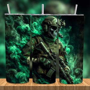 Puede incluir: Un vaso con una ilustración digital de un soldado con rostro de calavera, que lleva un casco y equipo militar. El diseño incluye efectos de humo verde y un rifle. El vaso tiene una pajita plateada.