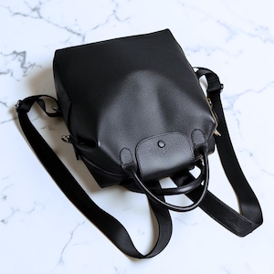 Puede incluir: Un juego de tres tazas de cerámica con un acabado moteado y mate. Las tazas son en tonos crema, gris claro y gris oscuro. Cada taza tiene un diseño simple y moderno y un asa redondeada. Las tazas están apiladas una encima de la otra.