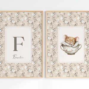Op de afbeelding: Twee ingelijste kunstprints. Eén toont de letter "F" en de naam "Frankie" in een lichtbeige lijst met een bloemenpatroon. De andere print toont een slapende muis in een theekopje, ook in een bloemenframe.