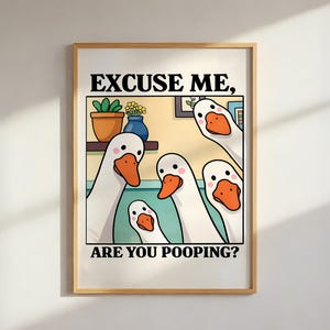Peut inclure: Une affiche encadrée avec une illustration de dessins animés d'oies blanches avec des becs et des pieds orange. Le texte "EXCUSE ME, ARE YOU POOPING?" est imprimé en noir. L'arrière-plan comprend une étagère avec des plantes et un vase bleu.