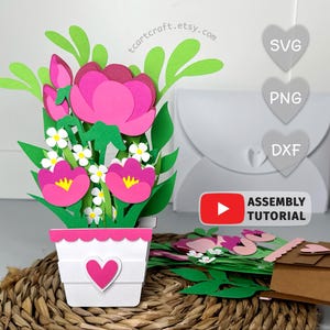 May include: A paper flower arrangement in a white pot with a pink heart. The arrangement includes pink and white flowers with green leaves. A white envelope and a small brown box are also visible. The text "tcartcraft.etsy.com" is in the image.