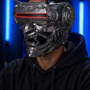 May include: A futuristic, metallic mask with a red illuminated visor and intricate detailing. The mask has a menacing, angular design, with a prominent mouth area. The overall aesthetic suggests a cyberpunk or sci-fi theme.