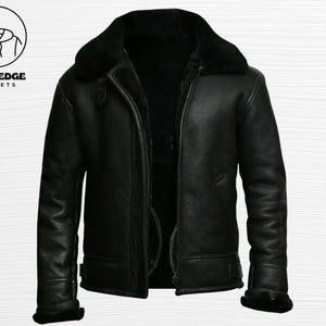 Può includere: Giacca in pelle nera con colletto e fodera in montone. La giacca ha una chiusura con cerniera e un classico stile aviatore. Il logo Bold Edge Jackets si trova in alto a sinistra.