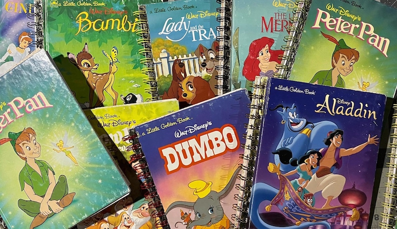 May include: A collection of spiral-bound notebooks featuring classic Disney Little Golden Book covers, including titles such as Bambi, Lady and the Tramp, The Little Mermaid, Peter Pan, Dumbo, and Aladdin, showcasing colorful character illustrations.