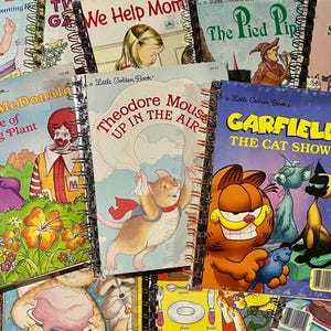 May include: A collection of vintage Little Golden Books with colorful illustrations and titles. Featured titles include "Ronald McDonald and the Tale of the Talking Plant" and "Garfield: The Cat Show". The books have spiral bindings and are in various conditions.