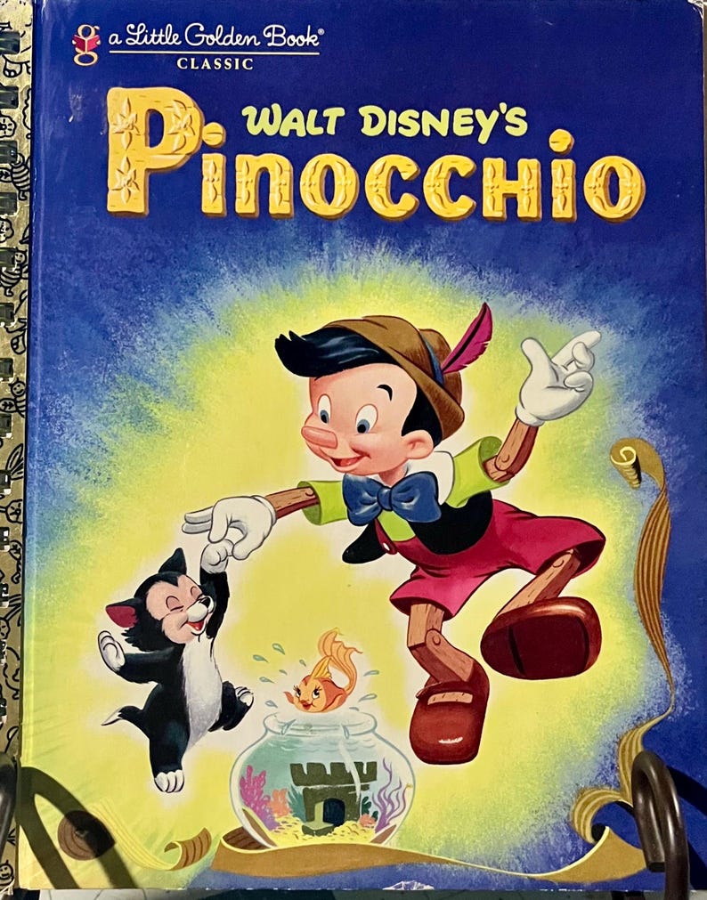 May include: A Little Golden Book titled Walt Disney's Pinocchio with a blue cover featuring the character Pinocchio, a black and white cat, and a goldfish in a bowl. The title is printed in large yellow letters at the top of the book cover.