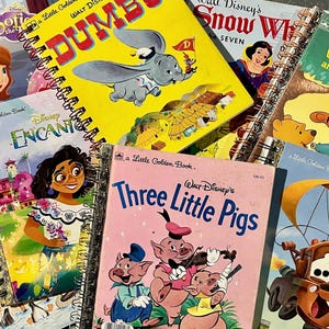 May include: A collection of spiral-bound Little Golden Books featuring various Disney characters including Dumbo, Snow White, Winnie the Pooh, Encanto, Three Little Pigs, and Cars. The books are arranged in a overlapping stack with colorful illustrations.