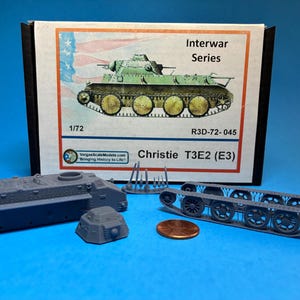 May include: A model kit of a Christie T3E2 (E3) tank, part of the Interwar Series. The kit includes several grey plastic components, a box with a tank illustration, and a penny for scale. The box has the text "1/72" and "R3D-72-045".
