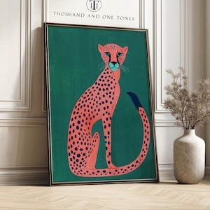 Modern art print of a pink spotted cheetah on a deep teal background with a playful modern mood, framed art print leaning against a white paneled wall by a tall window and vase of dried branches.
