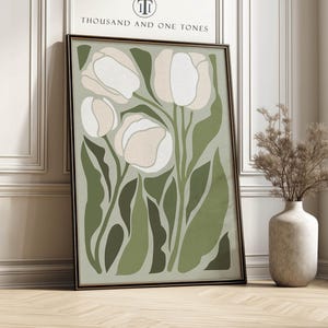 Stylized tulip art print in sage greens and cream with a calm modern mood, physical wall art print leaning against a white paneled wall beside a tall window and a vase of dried branches.