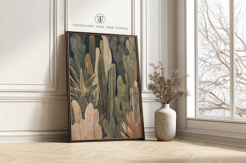 Hand-drawn cactus and tropical leaves in olive and beige on a dark background, modern botanical wall art print leaning against a white paneled wall beside a tall window.
